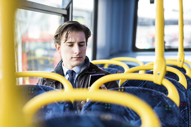 Großbritannien, London, Porträt eines Geschäftsmannes, der im Bus sitzt und auf sein Handy schaut - WPEF00175