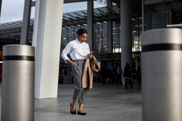 Smiling businesswoman looking at cell phone - MAUF01374