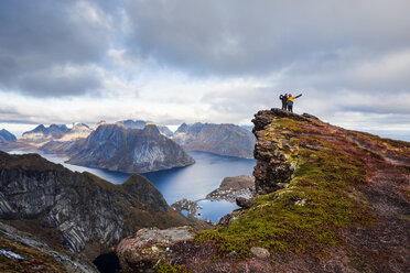 Norwegen, Lofoten, Reine, Männer mit erhobenen Armen stehen auf Reinebringen - WVF01091