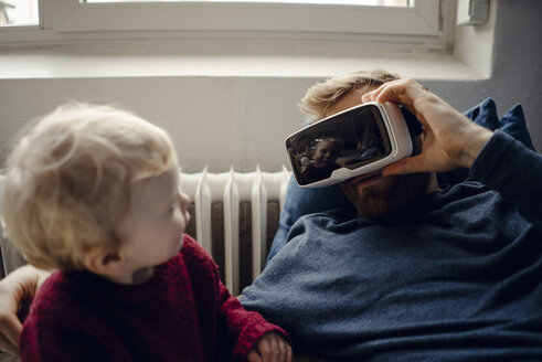 Father and son playing with VR glasses at home - KNSF03698