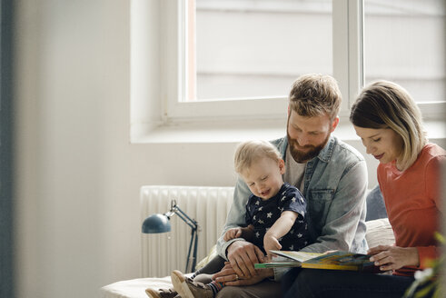 Kleiner Junge sitzt auf dem Schoß des Vaters, die Mutter liest ein Kinderbuch vor - KNSF03705