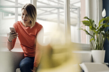 Woman using smartphone at home - KNSF03718