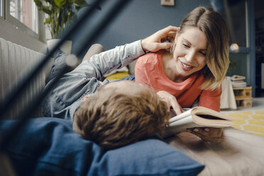 Happy couple reading and cuddling at home - KNSF03721