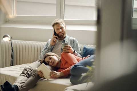 Happy couple reading and cuddling at home stock photo