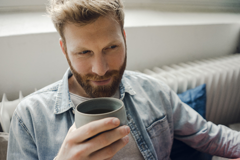 Mann entspannt sich zu Hause und trinkt Kaffee, lizenzfreies Stockfoto