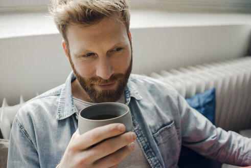 Mann entspannt sich zu Hause und trinkt Kaffee - KNSF03730