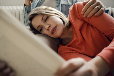 Happy couple reading and cuddling at home - KNSF03731