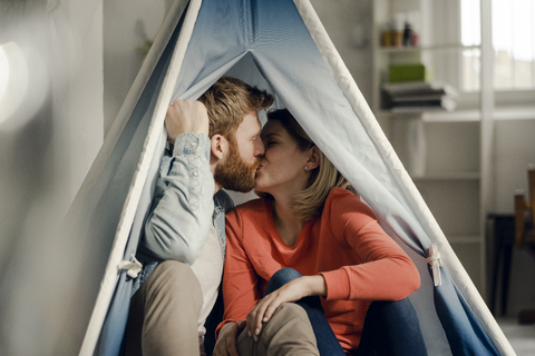 Glückliches Paar zu Hause beim Zelten im Wohnzimmer, lizenzfreies Stockfoto