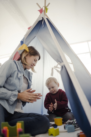 Mother playing with her son in a tent at home stock photo