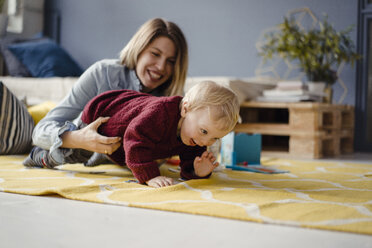 Mutter und Sohn spielen zu Hause, das Baby lernt zu krabbeln - KNSF03773