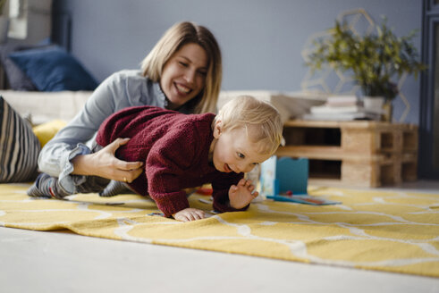 Mutter und Sohn spielen zu Hause, das Baby lernt zu krabbeln - KNSF03773