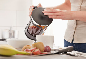 Frau gießt Kaffee in eine Tasse - MASF00332