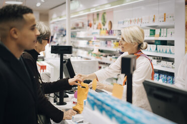 Apotheker und Kunden stehen an der Kasse in einem medizinischen Geschäft - MASF00385