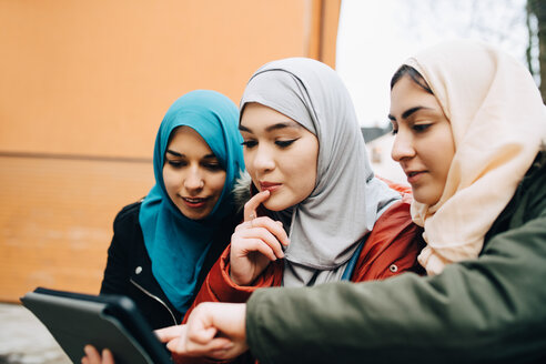 Junge muslimische Freundinnen teilen sich ein digitales Tablet in der Stadt - MASF00432