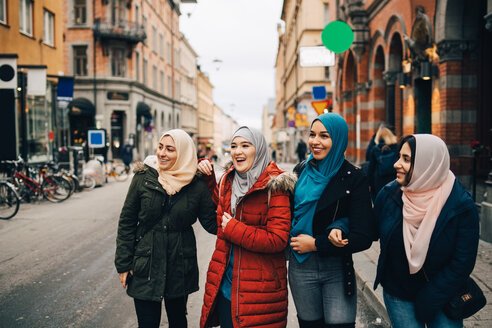 Glückliche multiethnische muslimische Freundinnen stehen auf der Straße in der Stadt - MASF00446