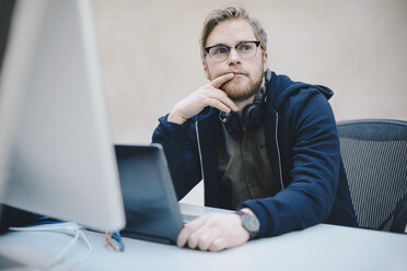 Nachdenklicher Computerprogrammierer sitzt am Schreibtisch im Büro - MASF00485