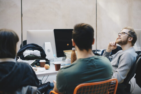 Nachdenklicher Computerprogrammierer sitzt mit Kollegen im Büro - MASF00490