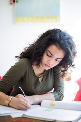 Jugendliches Mädchen studiert am Tisch und schreibt in ein Buch - MASF00571