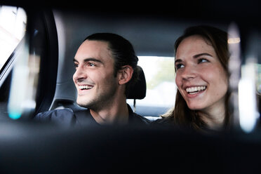 Lächelnde junge Freunde schauen durch das Fenster, während sie im Taxi fahren - MASF00587