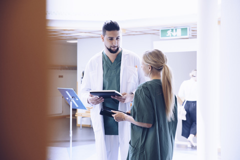 Junger Arzt im Gespräch mit einer Krankenschwester in der Krankenhauslobby, lizenzfreies Stockfoto