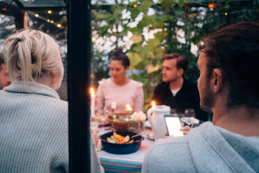 Junge männliche und weibliche Freunde beim Abendessen in einer Glaskabine - MASF00652