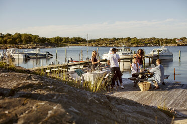 Young multi-ethnic friends enjoying summer at harbor against sky on sunny day - MASF00682