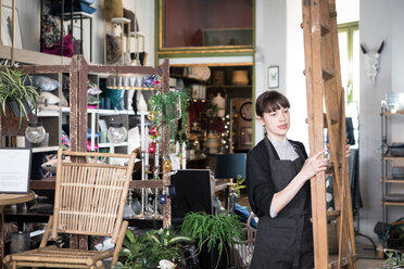 Young female entrepreneur carrying ladder at store - MASF00689