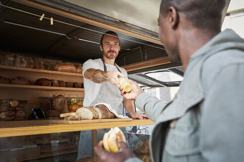 Young salesman giving bottle to male customer at food truck - MASF00730