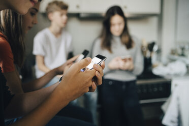 Close-up of friends using mobile phones at kitchen - MASF00739