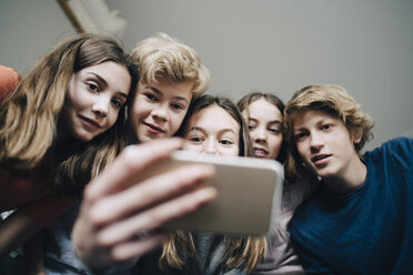 Niedriger Blickwinkel von Freunden, die ein Selfie mit ihrem Smartphone zu Hause machen - MASF00754
