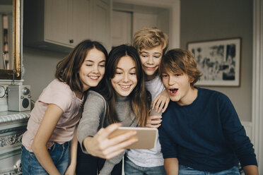 Cheerful friends taking selfie through smart phone while standing at home - MASF00757