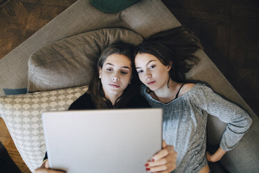 Hochformatige Ansicht von Mädchen, die einen Laptop benutzen, während sie zu Hause auf dem Sofa liegen - MASF00794