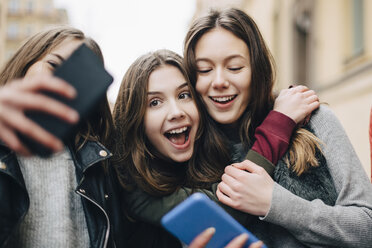 Mädchen nimmt Selfie mit weiblichen Freunden durch Handy in der Stadt - MASF00811