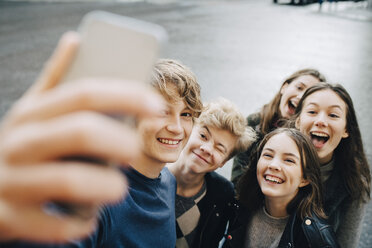Lächelnder Mann, der ein Selfie mit Freunden über sein Smartphone macht, während er in der Stadt steht - MASF00816