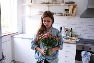 Frau mit Blumenvase in der Küche stehend - MASF00818