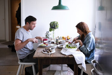 Seitenansicht eines Paares beim Essen am Tisch, das an der Wand sitzt - MASF00824