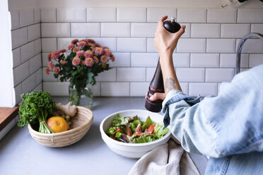 Cropped image of woman seasoning salad at kitchen counter - MASF00842