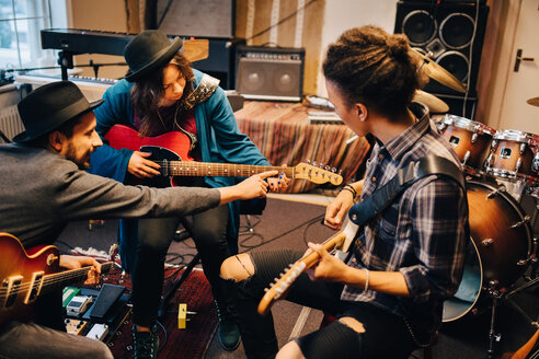 Mann unterrichtet Freundin beim Gitarrenspiel im Tonstudio während der Proben - MASF00851