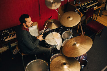 Mature man playing drum set while practicing at recording studio - MASF00855