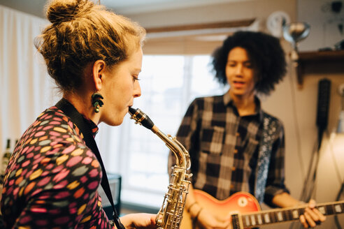 Männliche und weibliche Freunde spielen Saxophon und Gitarre beim Üben im Tonstudio - MASF00856