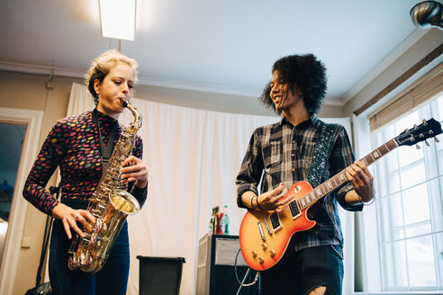 Freunde spielen Saxophon und Gitarre beim Üben im Tonstudio - MASF00857