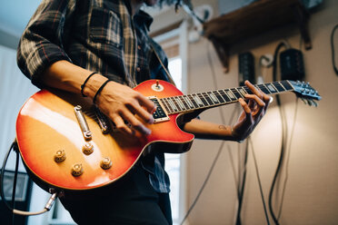 Mittelteil eines Mannes, der Gitarre spielt, während er im Aufnahmestudio übt - MASF00858