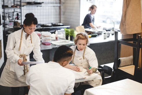 Multiethnische Restaurantbesitzer, die am Tisch sitzend diskutieren - MASF00866