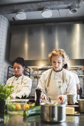 Weibliche Köche bei der Zubereitung von Speisen am Küchentisch in einem Restaurant - MASF00895