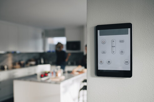 Thermostat-App auf digitalem Tablet, das über einer weißen Wand im Haus angebracht ist - MASF00914