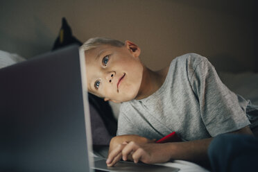 Junge mit Laptop auf dem Bett liegend zu Hause - MASF00934