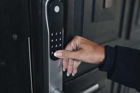 Abgeschnittene Hand einer Frau, die den Kombinations-Sicherheitscode an der Haustür entriegelt - MASF00951
