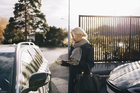 Ältere Frau steht neben Auto gegen Himmel - MASF00955