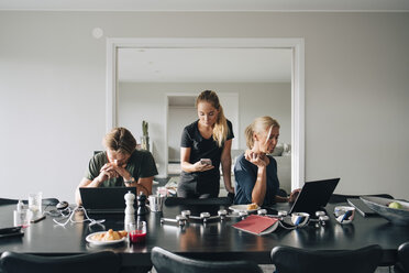 Family using technologies at dining table in room - MASF00963