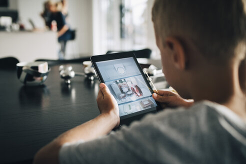 Rückansicht eines Jungen, der zu Hause ein digitales Tablet benutzt - MASF00966